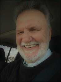 A man with white beard and smiling at the camera.