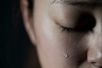 A close up of a person crying with one tear