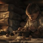 A child sitting on the ground with a bowl of food.